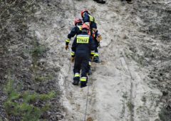 Strażacy z grupy wysokościowej znoszą ciało spadochroniarza