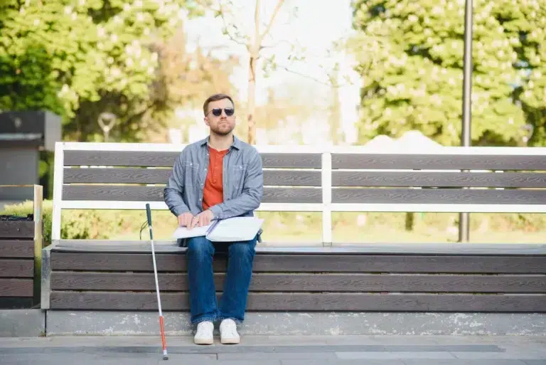 Blind man reading book on bench in park 2023 11 27 05 07 18 utc
